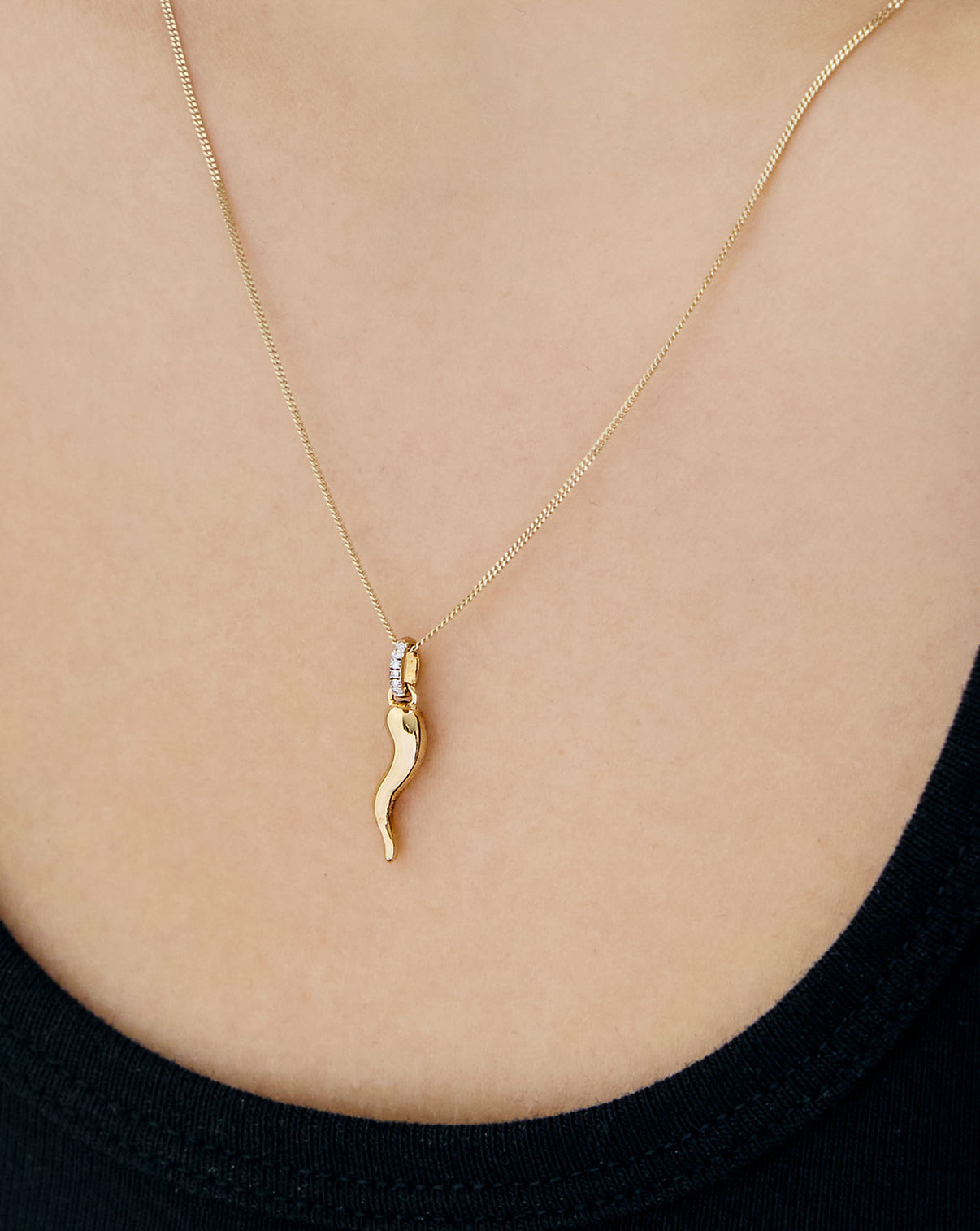 Cornicello charm pendant in 14K Yellow Gold and diamond clasp detail on a yellow gold necklace worn on model