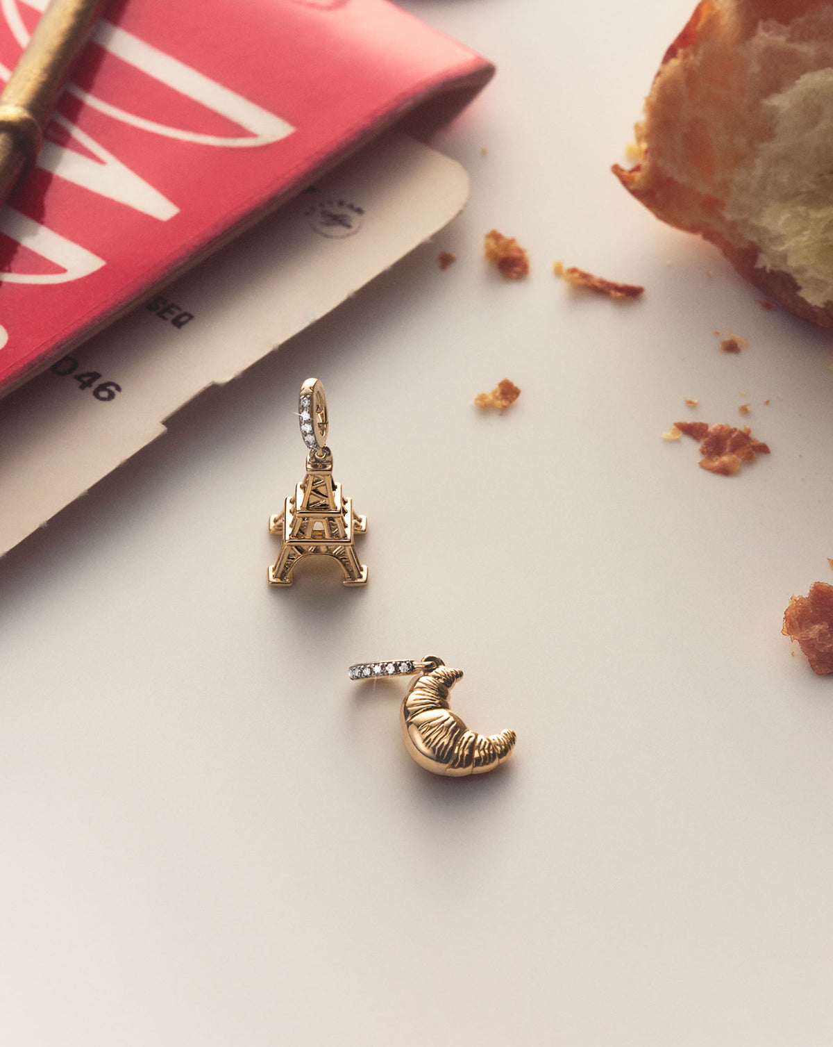 Styled still shot of our 14k yellow gold croissant and Eiffel tower charms