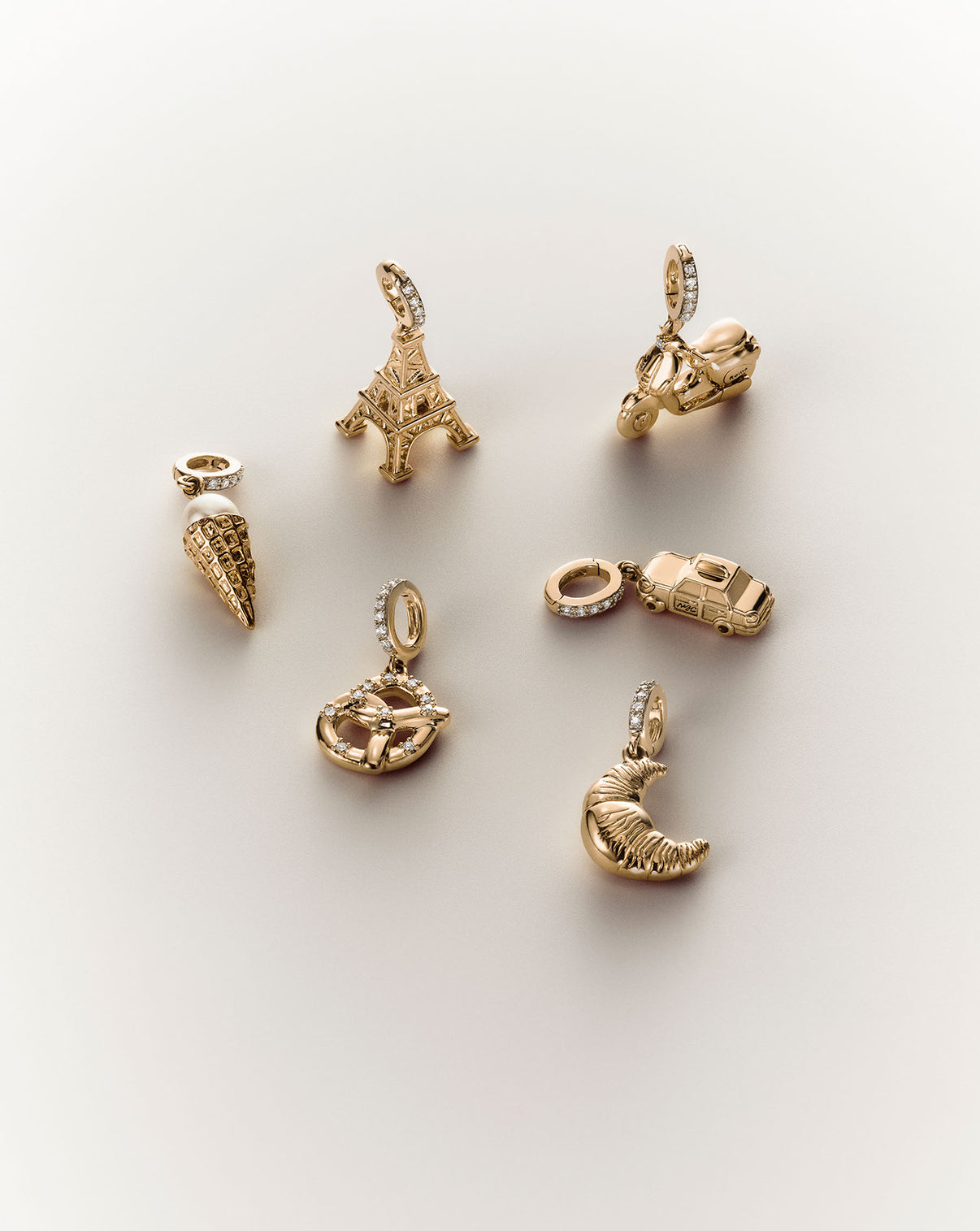Multiple products from our travel charm collection including the croissant, pretzel, Eiffel tower, NY taxi, gelato, and scooter charms.
