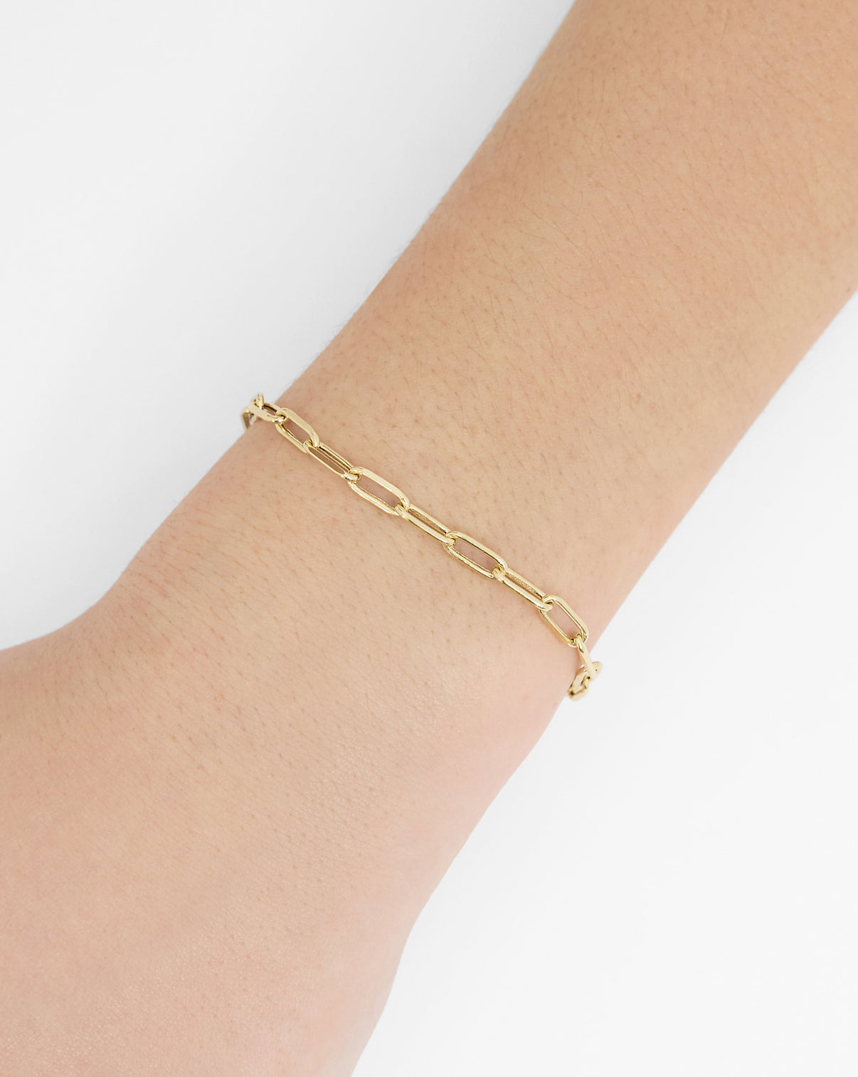 14k yellow gold Paperclip chain bracelet worn on model's arm