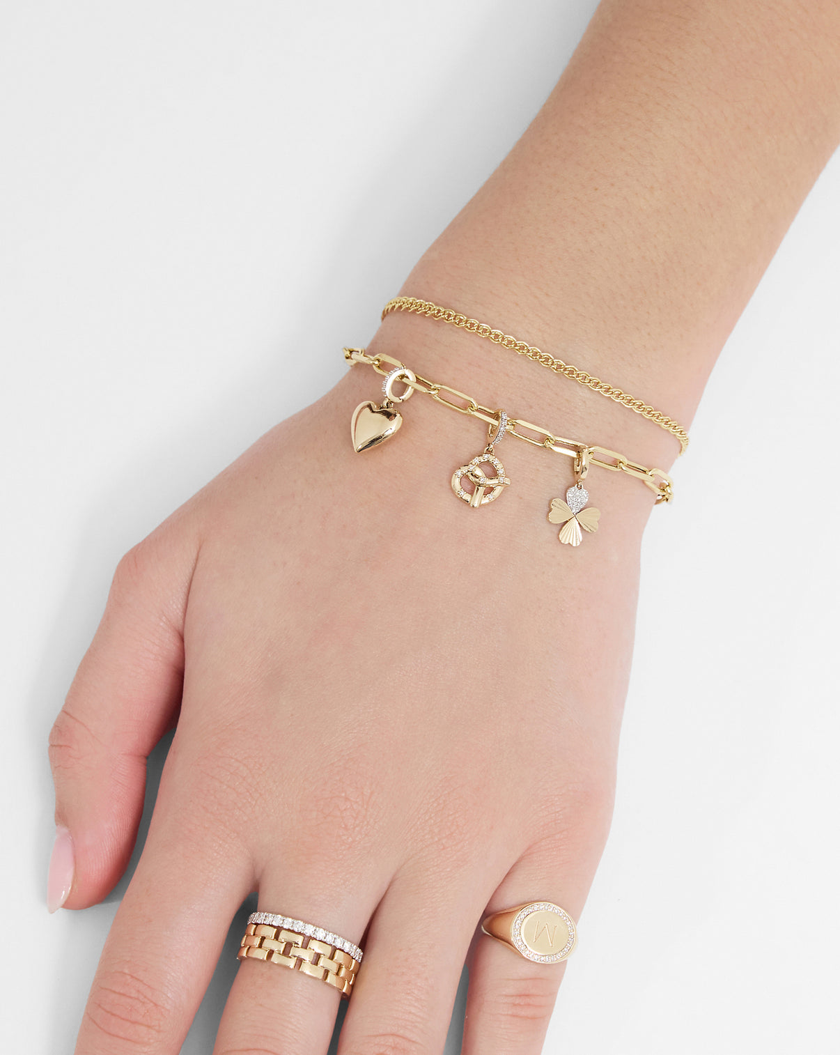 14k yellow gold Paperclip chain bracelet styled with heart, pretzel, and clover charms along side our Petite Twin Chain Bracelet
