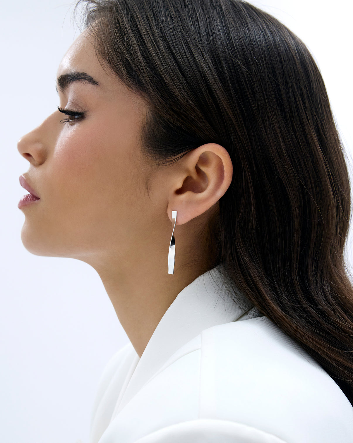 side profile of Silver Twist earrings on model with white blazer