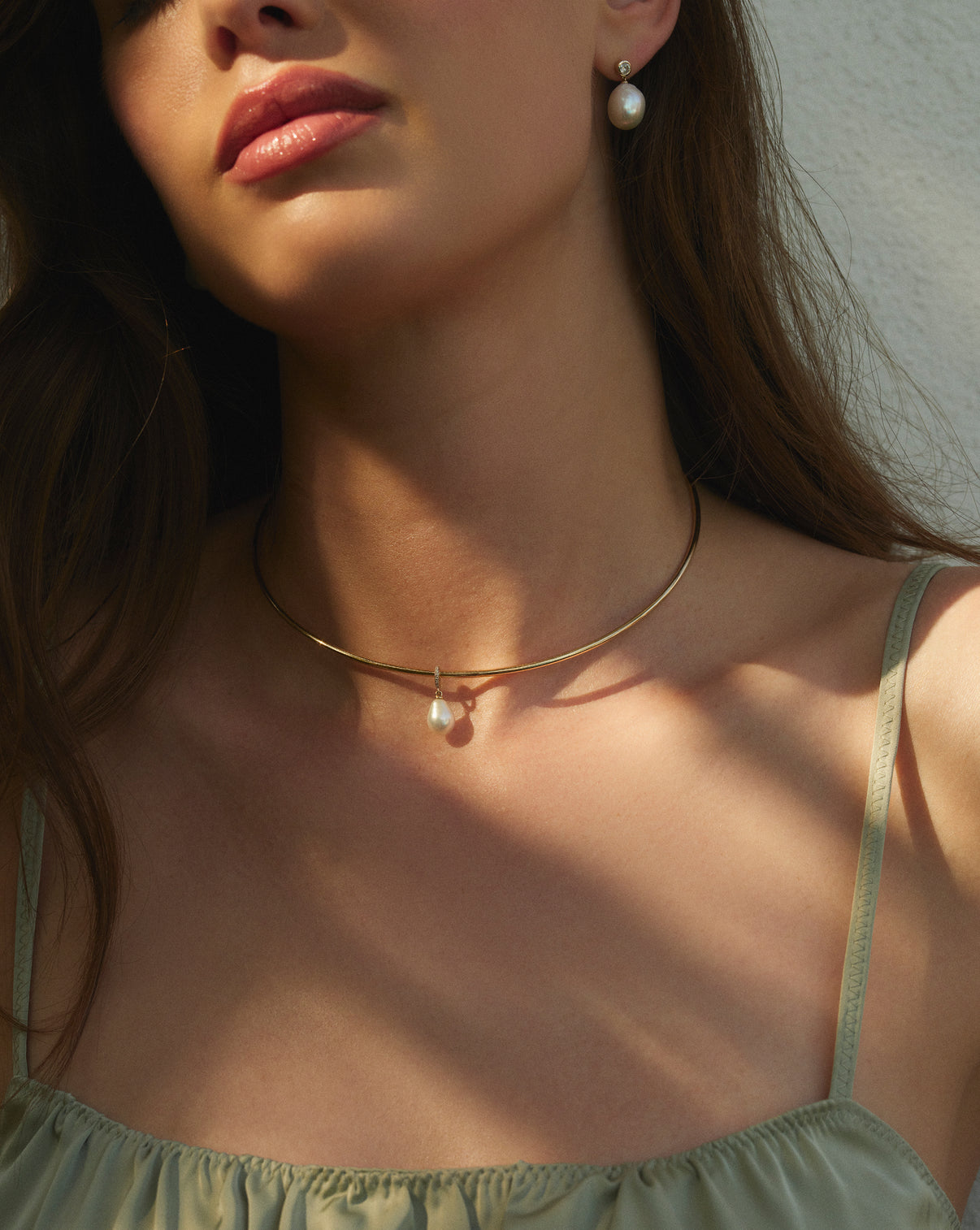 Close-up detail of 14k yellow gold collar necklace styled with pendants on-model