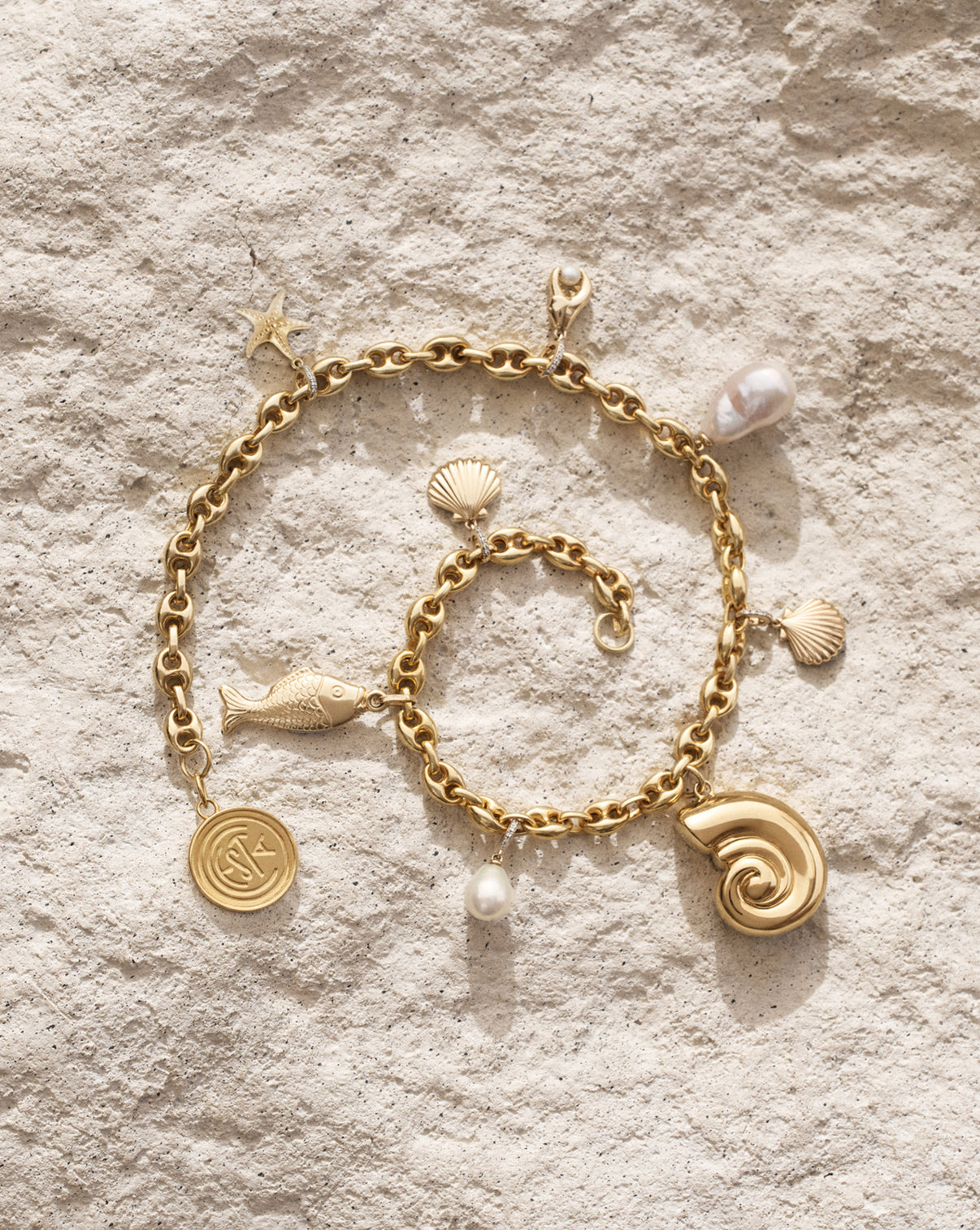 Detailed view of RC Bag Necklace featuring 14k gold seashell, fish, lobster claw, starfish charms, 14k gold vermeil over 925 sterling silver Nautilus shell and Cesta medallion pendant, and freshwater pearl charms