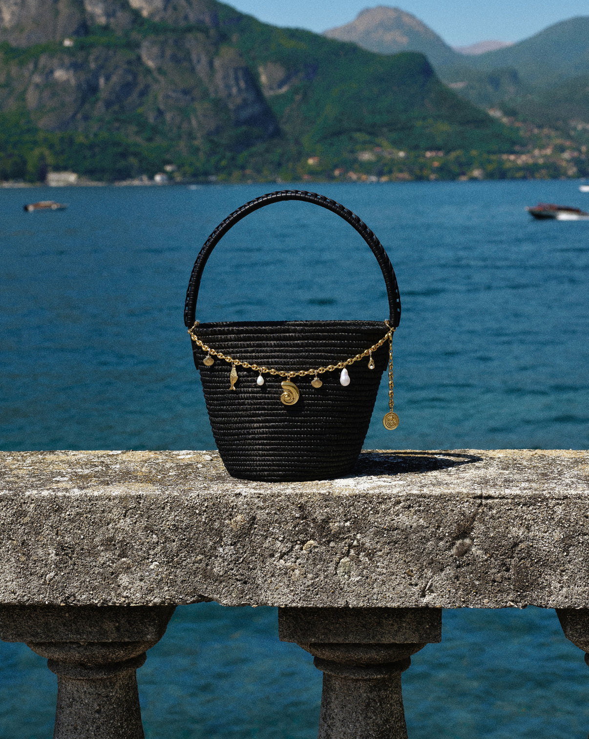 Lifestyle photo of the RC x Cesta Charmed Ladybag sitting on stone ledge