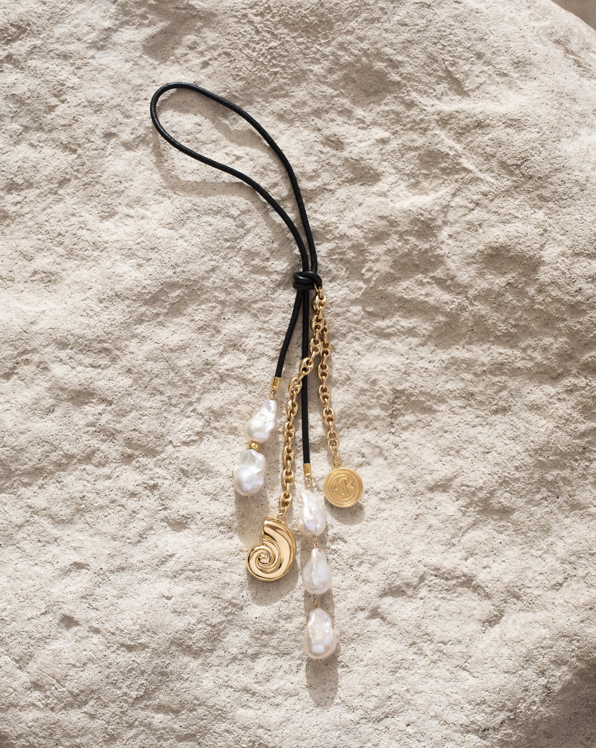 Close up of the Ring Concierge Bag Charm featuring leather cord and 14k gold vermeil over 925 sterling silver with 5 freshwater pearls