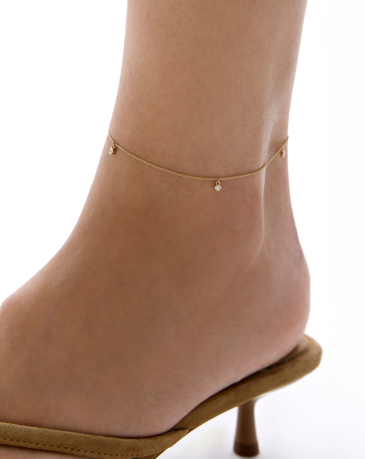 on-model image of yellow gold anklet with diamond drops with white background