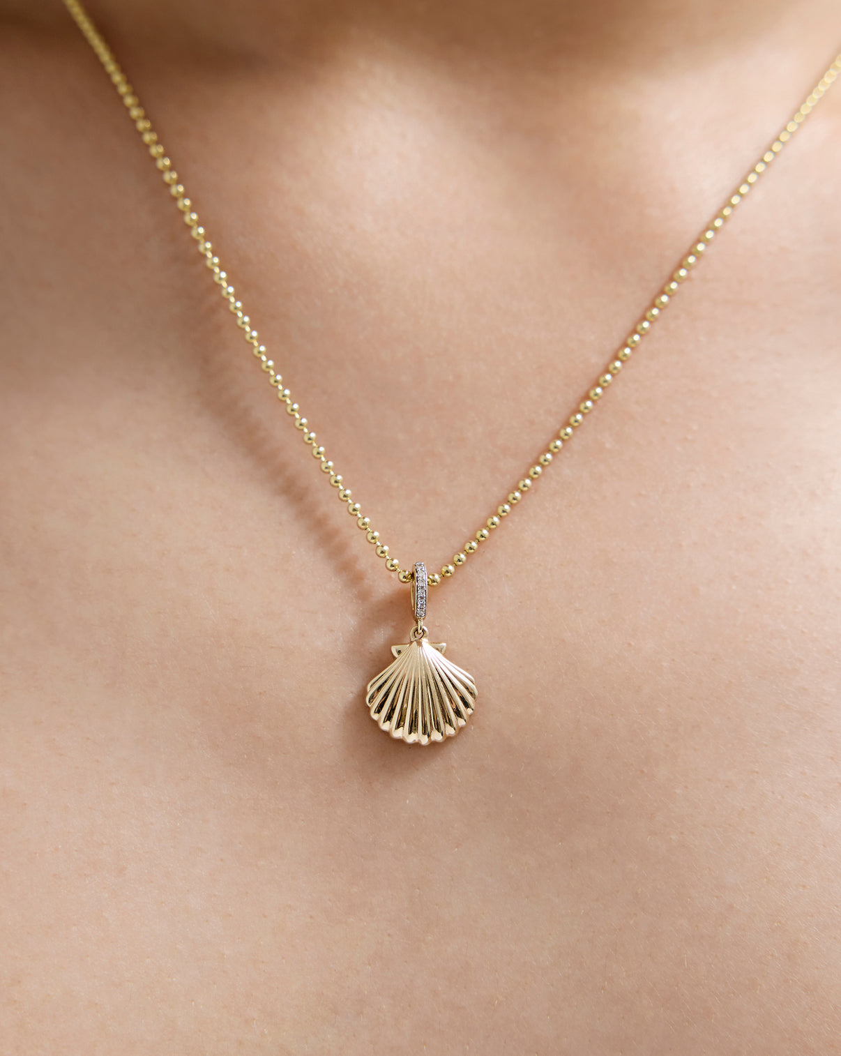 Gold Seashell Charm with detailed ridges and texture, shown on-model on bead necklace