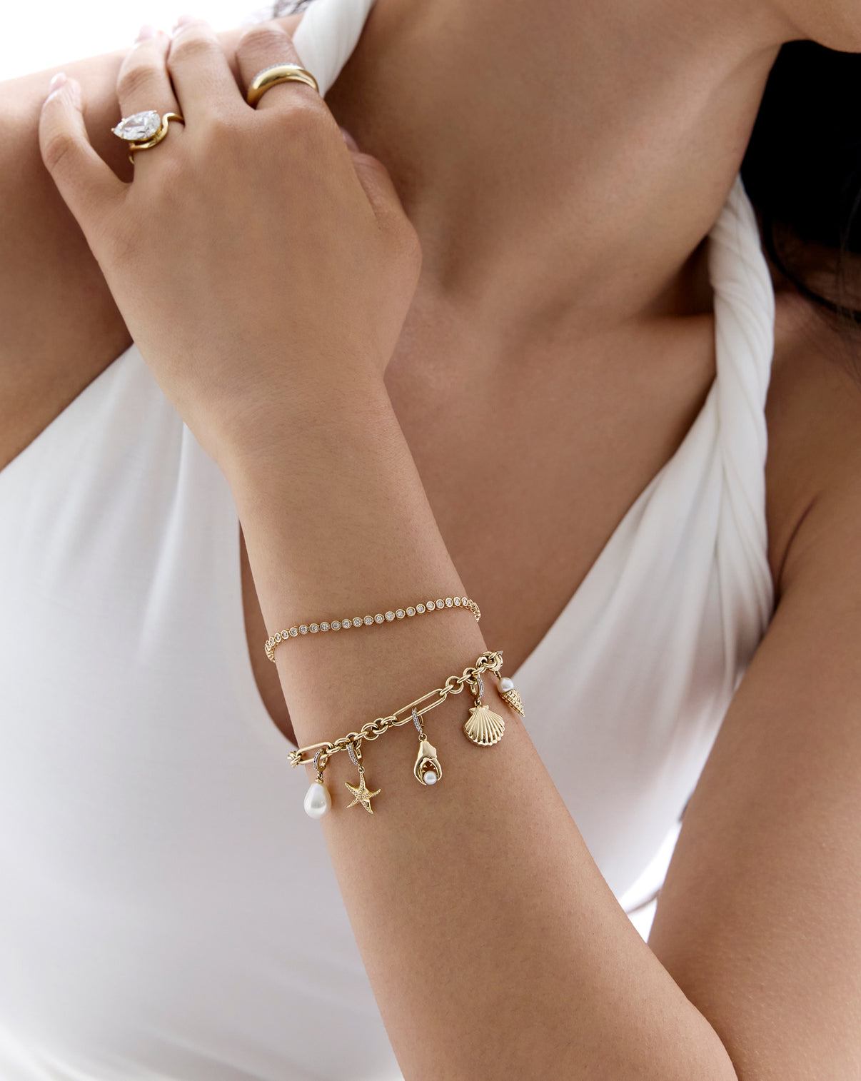 Gold Seashell Charm with detailed ridges and texture, shown on-model on charm bracelet with tennis bracelet