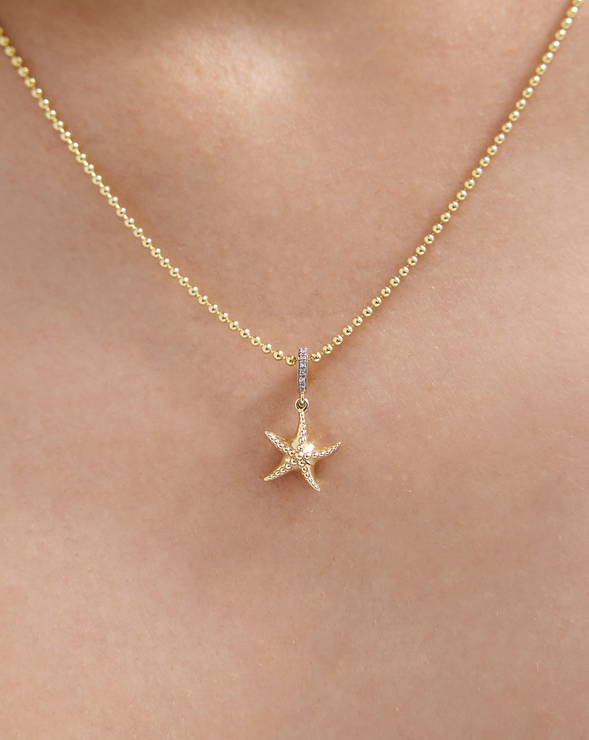 Close up of Sea Star Charm worn on gold necklace