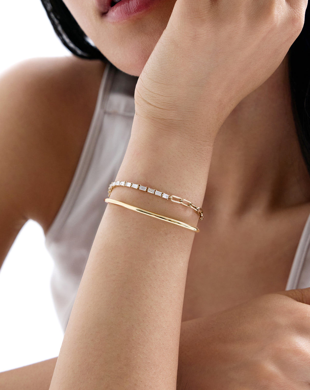 Close up of model wearing our 14k solid gold Baguette Lab Diamond Tennis Chain Bracelet paired with another gold bracelet