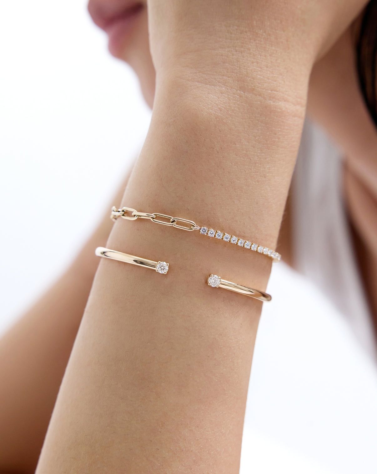 Close up of model wearing our 14k solid gold Round Lab Diamond Tennis Chain Bracelet paired with another gold bracelet