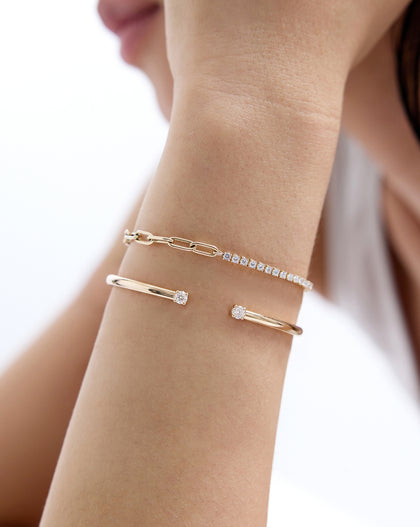 Close up of model wearing our 14k solid gold Round Lab Diamond Tennis Chain Bracelet paired with another gold bracelet