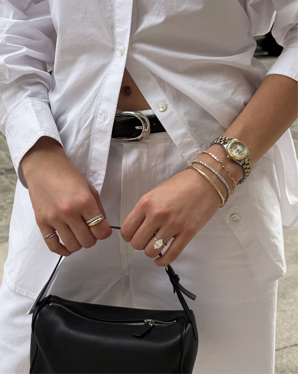 Lifestyle image of a model wearing our Baguette Lab Diamond Tennis Chain Bracelet along with a variety of other jewelry items