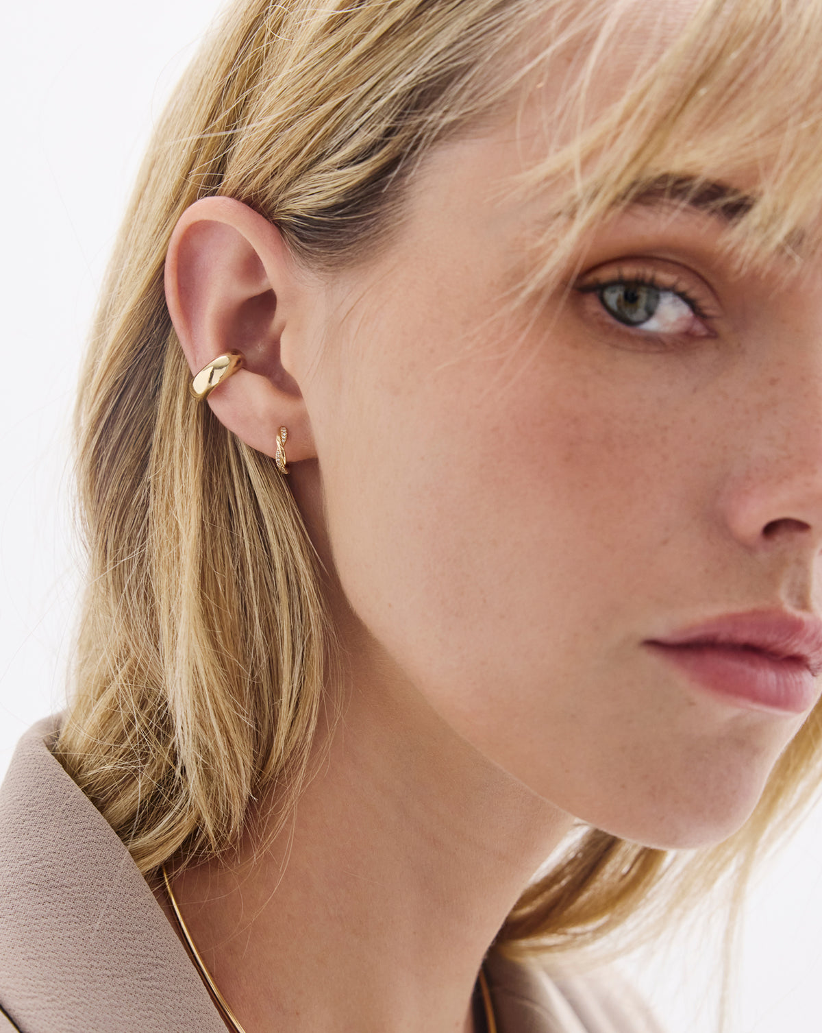 Close-up detail of diamond twist huggie earrings showing sparkling diamonds and intricate gold craftsmanship