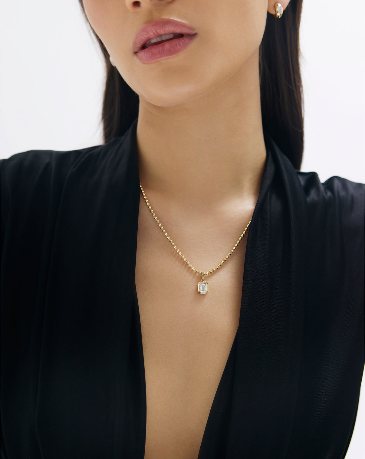 Close-up detail of 14k gold bead chain necklace showing an emerald pendant styled with it global