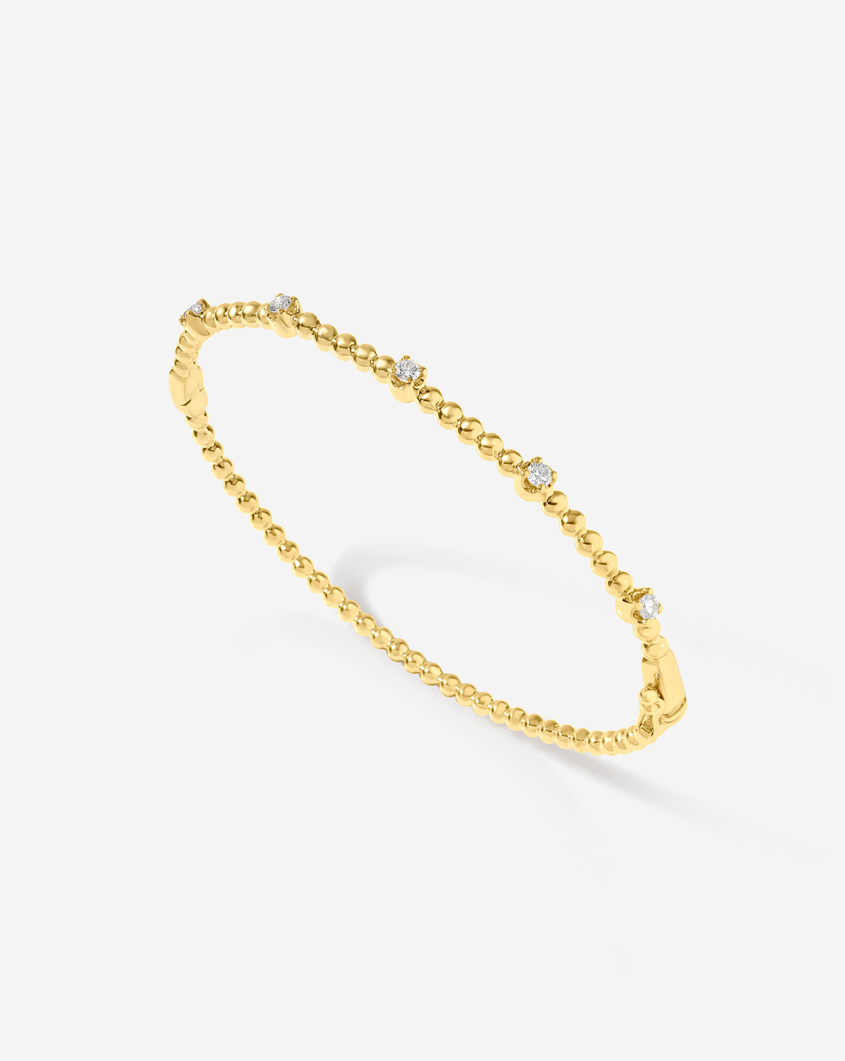 Close-up view of natural diamonds set in 14k gold ball bangle showing I-J color and SI clarity