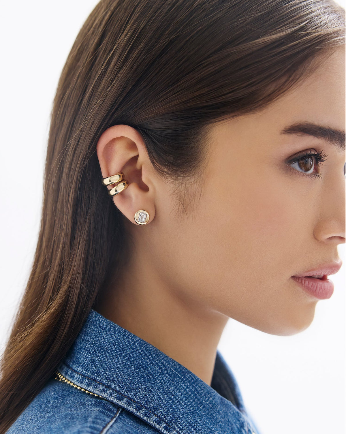 Close-up of a woman wearing gold earrings with a plain background