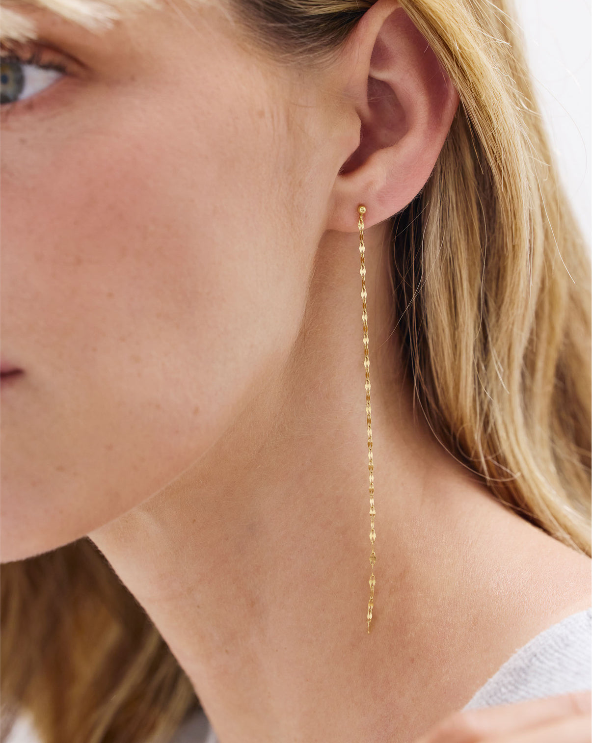 Side profile of model wearing Chain Dusters earrings by Ring Concierge - showcasing the elegant drape and movement of gold chain earrings