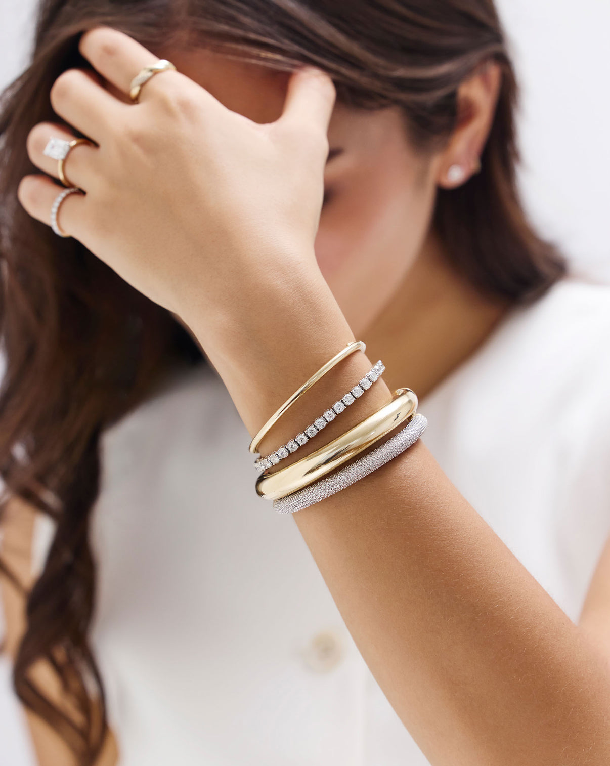Lifestyle shot of classic diamond tennis bracelet worn with other jewelry pieces for styling inspiration GLOBAL