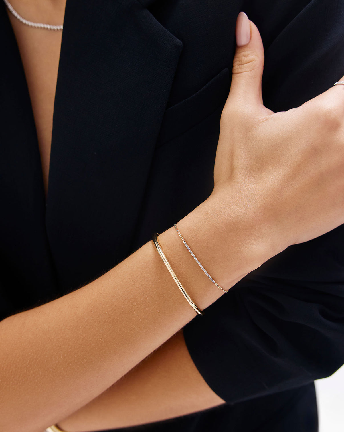 Model's hand showcasing diamond bar bracelet alongside other delicate gold jewelry