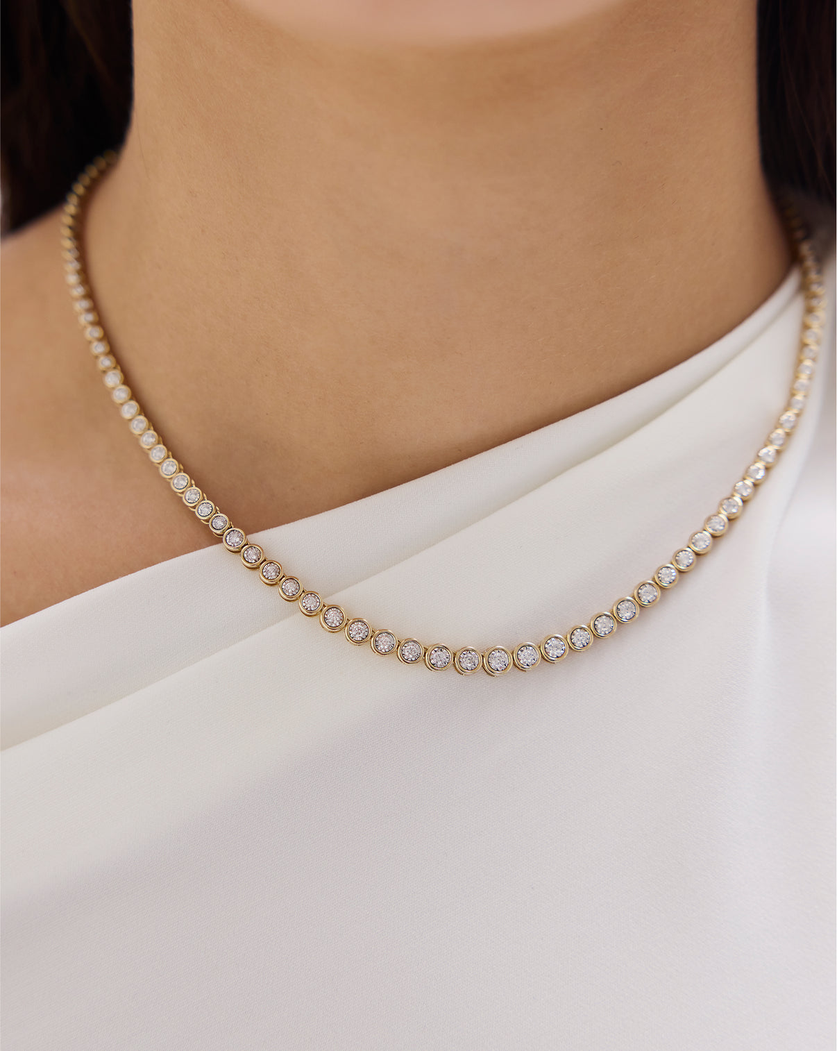 Close-up of graduated bezel diamond tennis necklace showing diamond size progression and gold bezel settings GLOBAL