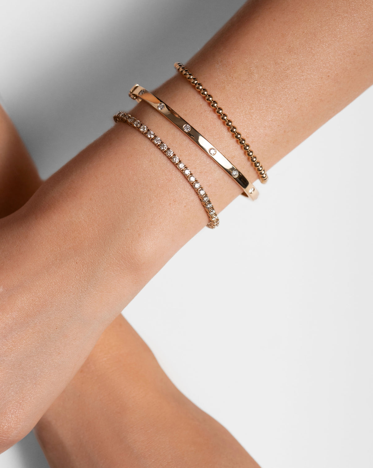 Model wearing Inlay Diamond Bangle with elegant hand positioning to show the bangle styled alongside other bracelets global