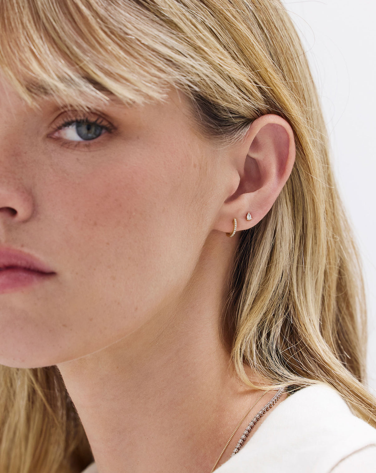 Model profile view wearing Petite Diamond Huggies, highlighting the elegant small hoop silhouette with pave diamonds