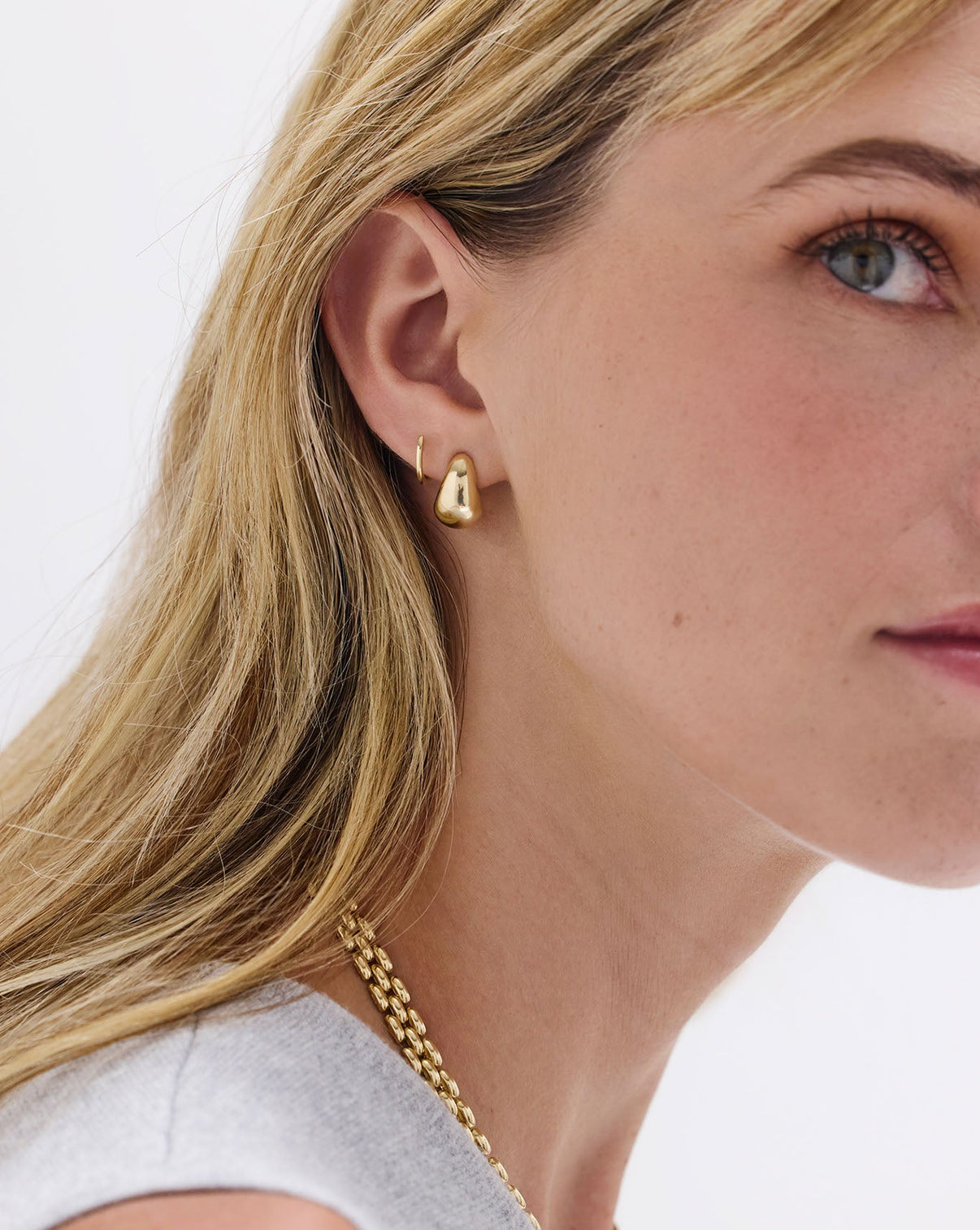 Petite Gold Huggies earrings styled with Gold Cloud Earrings on model's ear