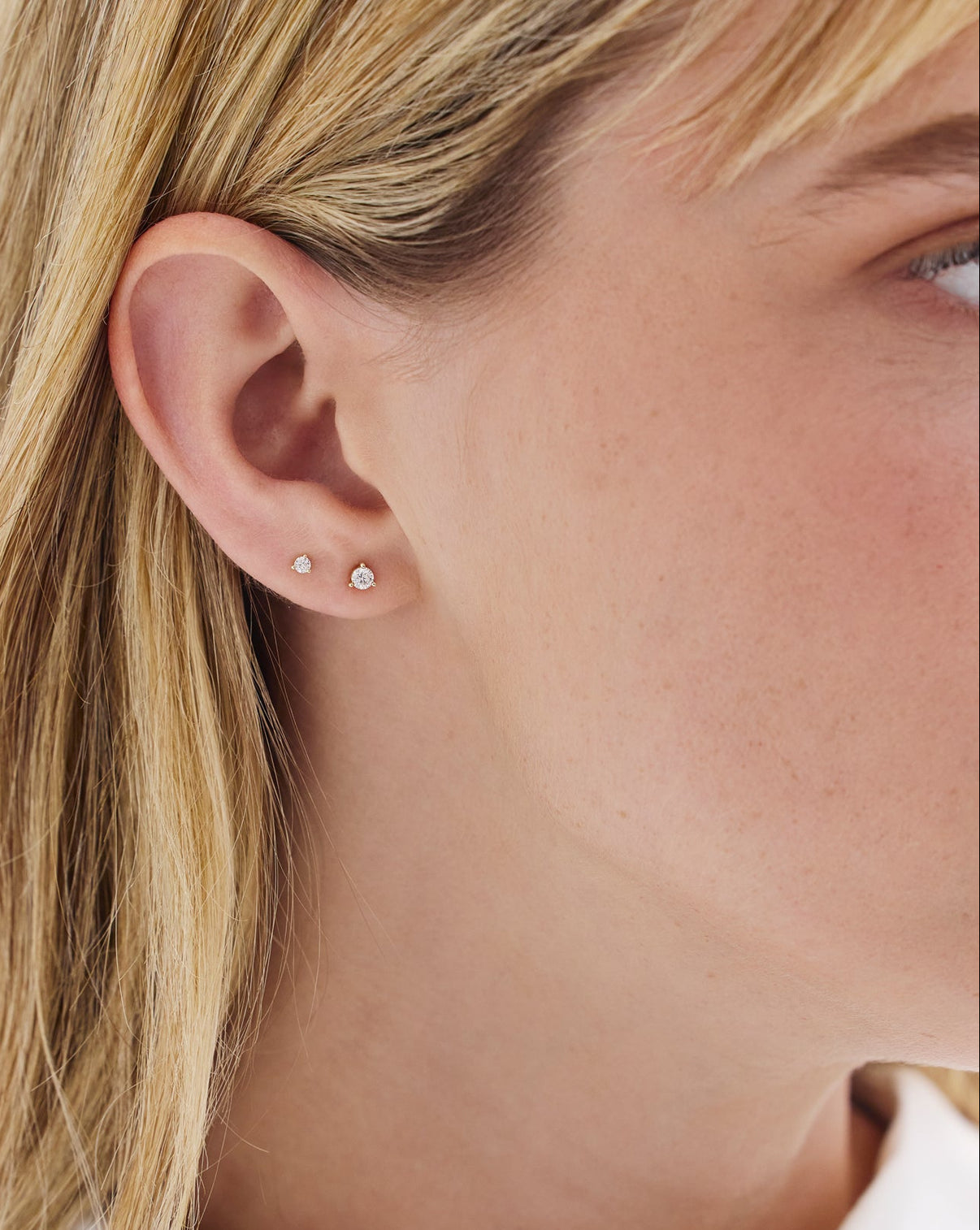 Ring Concierge's Tiny diamond stud earrings styled on model, showcasing delicate sparkle and size 
