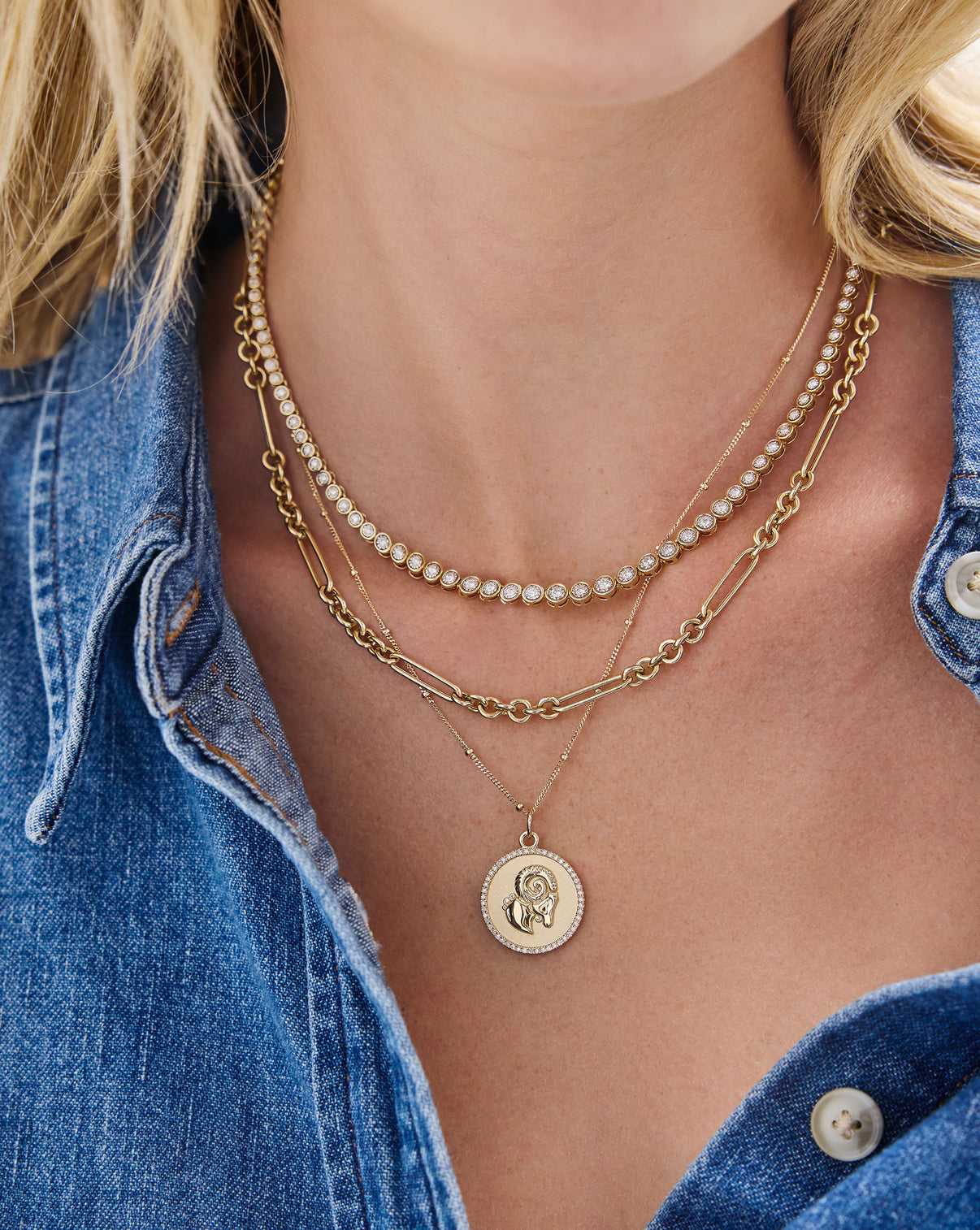 model wearing Ring Concierge Necklace with a medallion pendant featuring diamonds and the Zodiac sign stacked with a tennis necklace and chain link necklace global