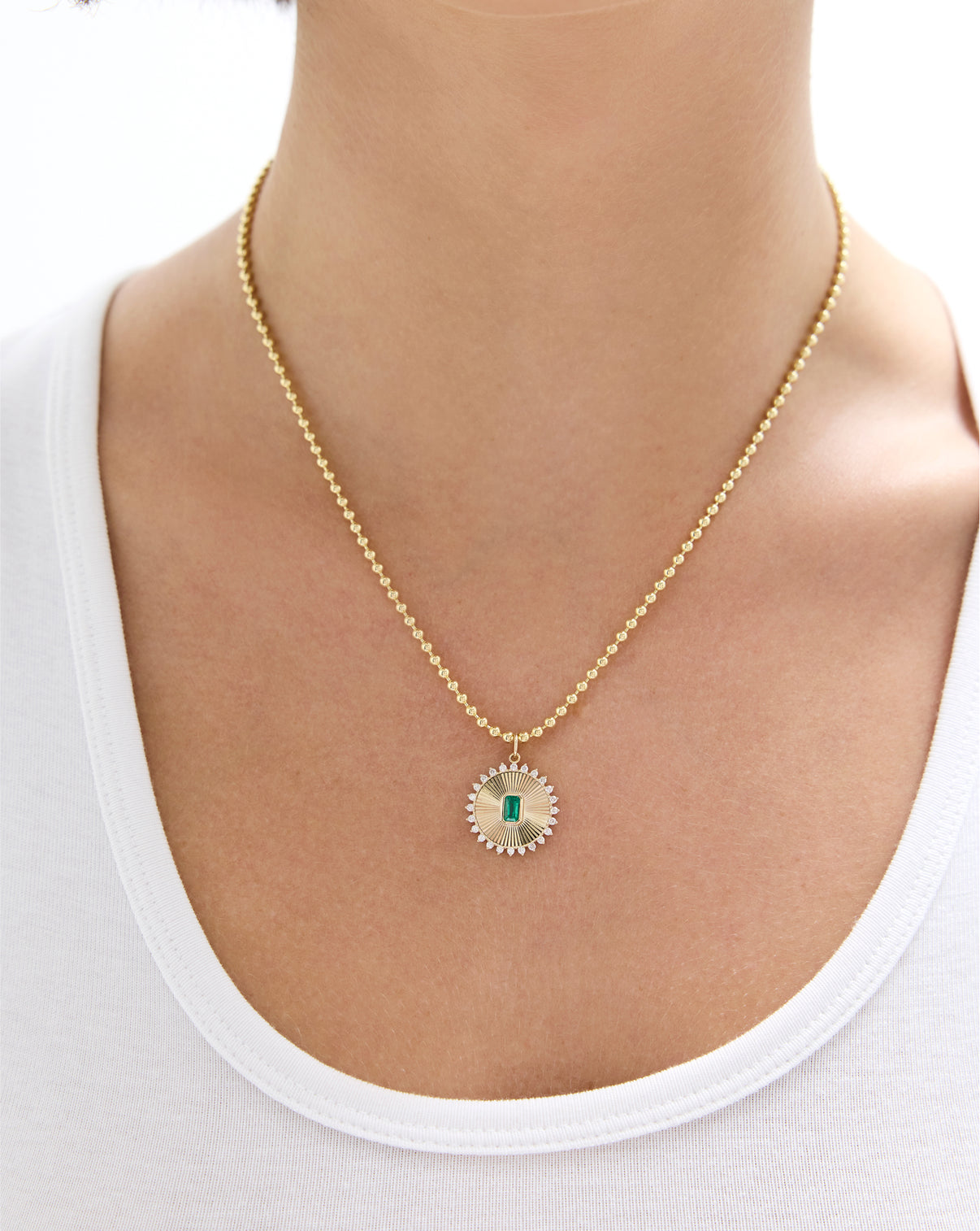 Close-up of fluted emerald pendant showing detailed gold texture and emerald cut stone