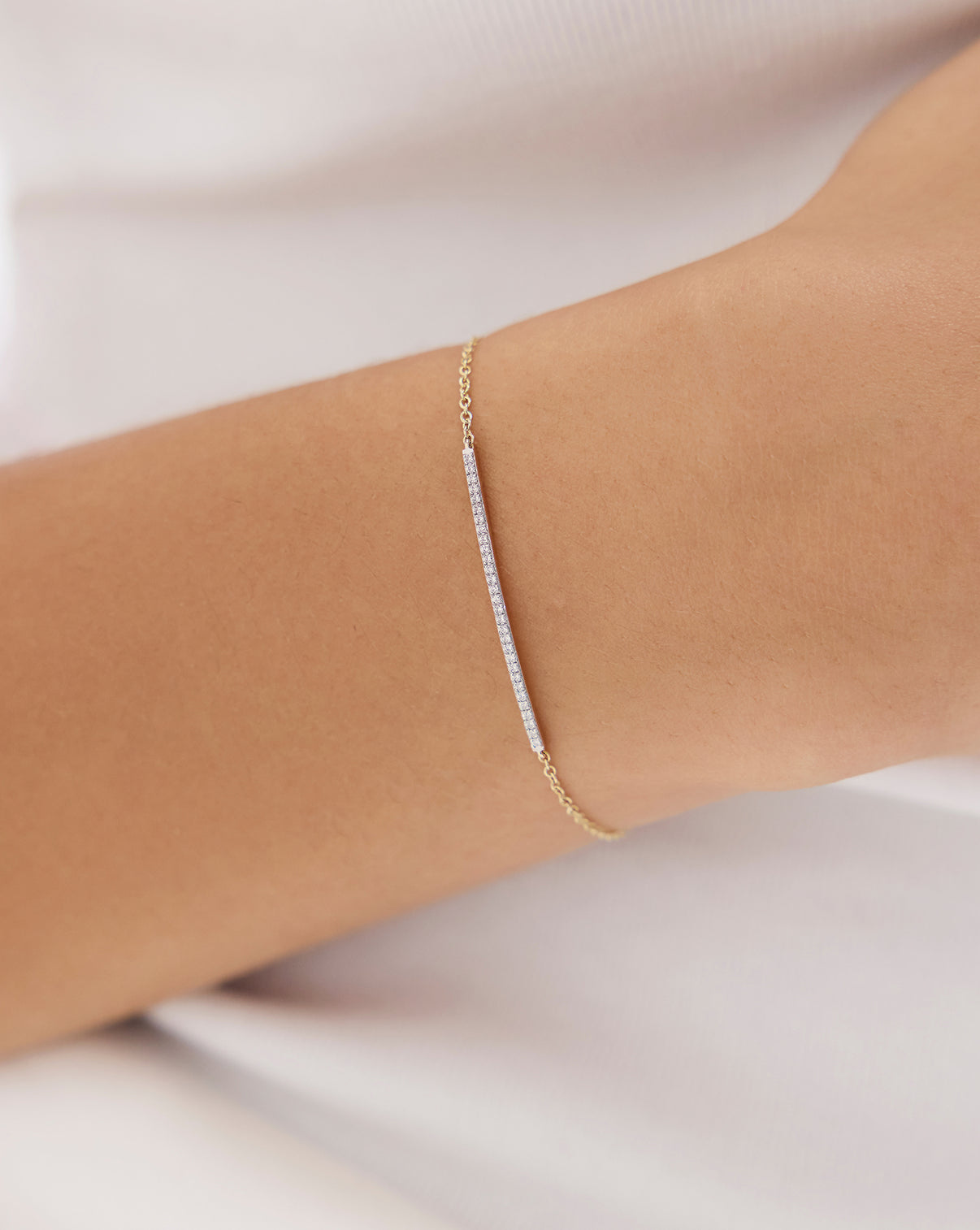 Woman wearing diamond bar bracelet on wrist, styled with casual white shirt