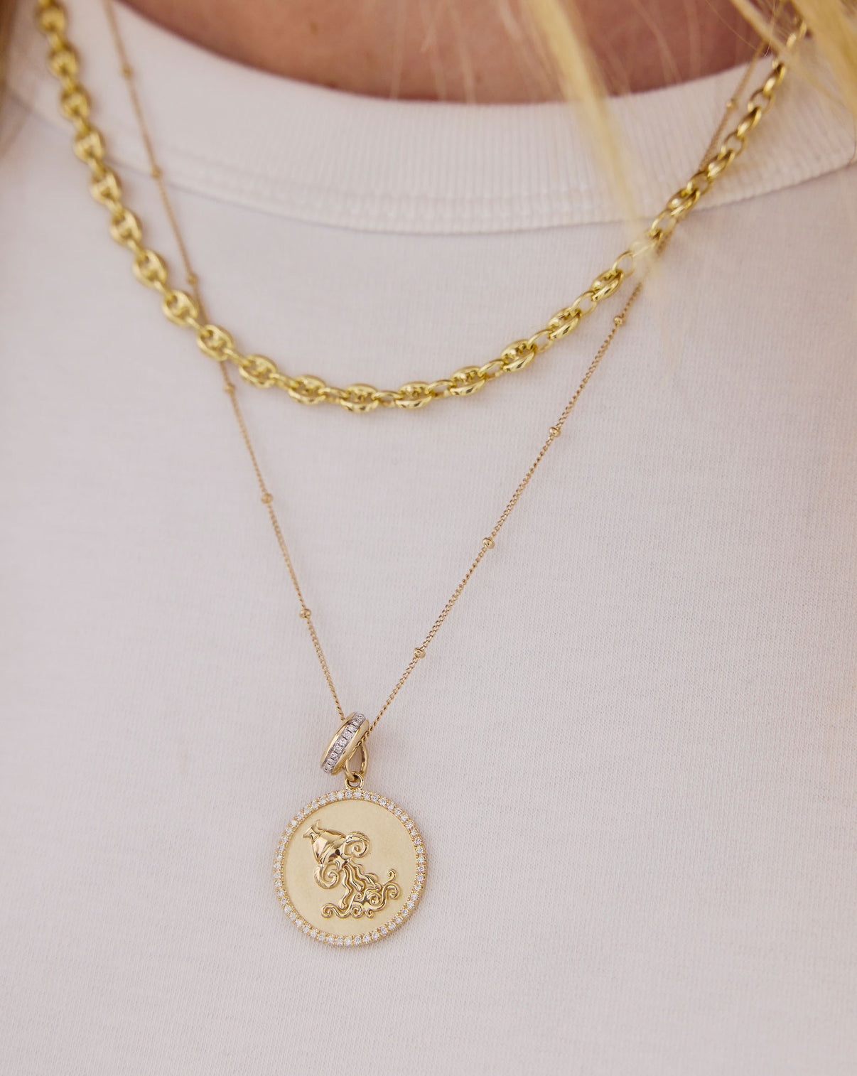 model wearing zodiac medallion necklace stacked with a delicat chain necklace global