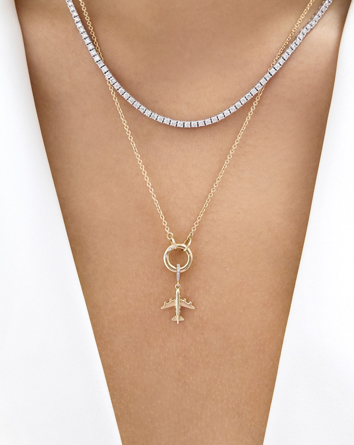 model wearing a tennis necklace and a gold necklace with airplane charm