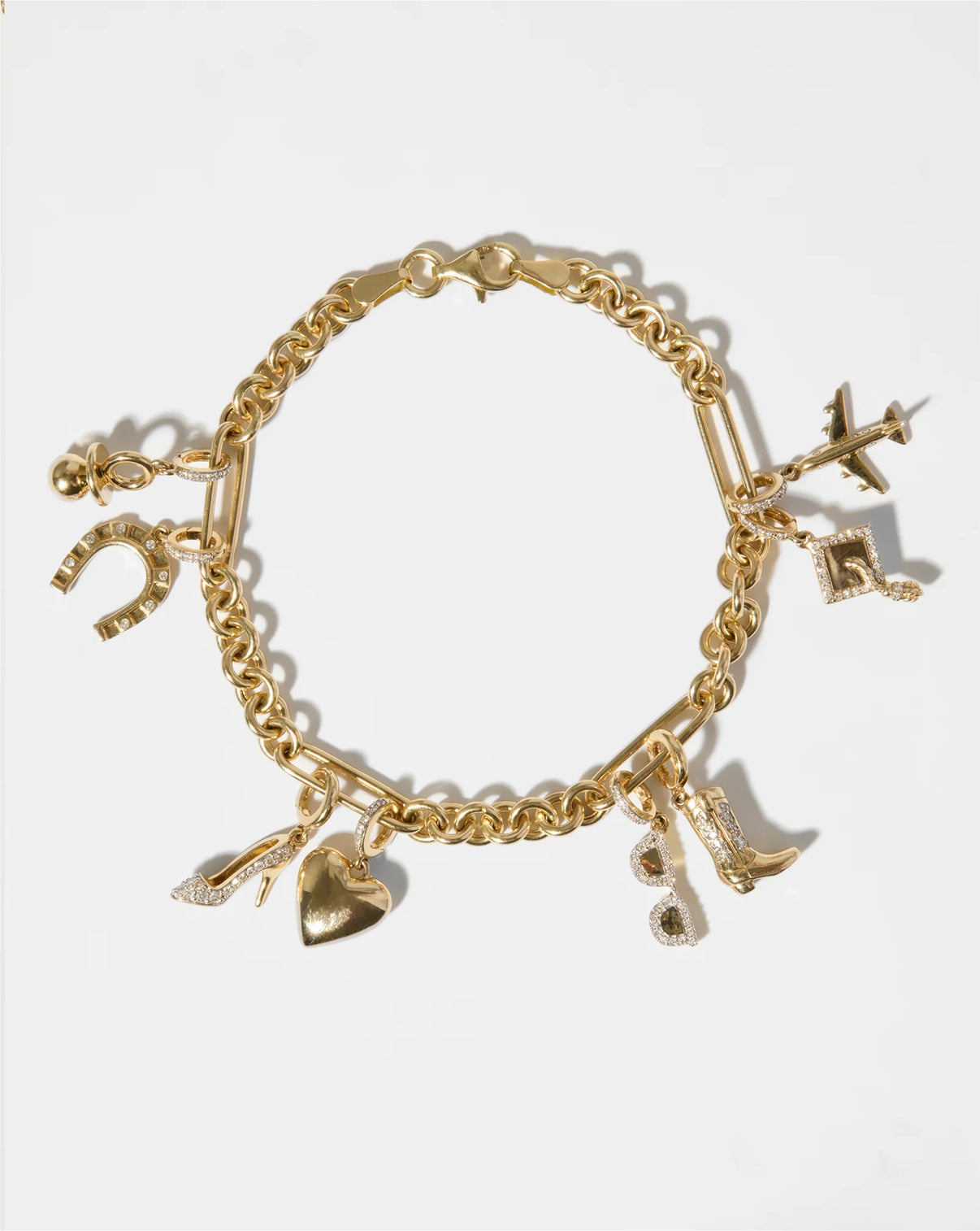 Flat lay image of gold bracelet with various diamond and gold charms