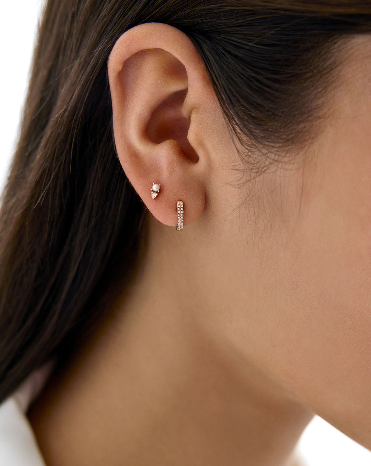 Close up of model's ear wearing the Pearl and Diamond Studs and Petite Double Row Diamond huggies