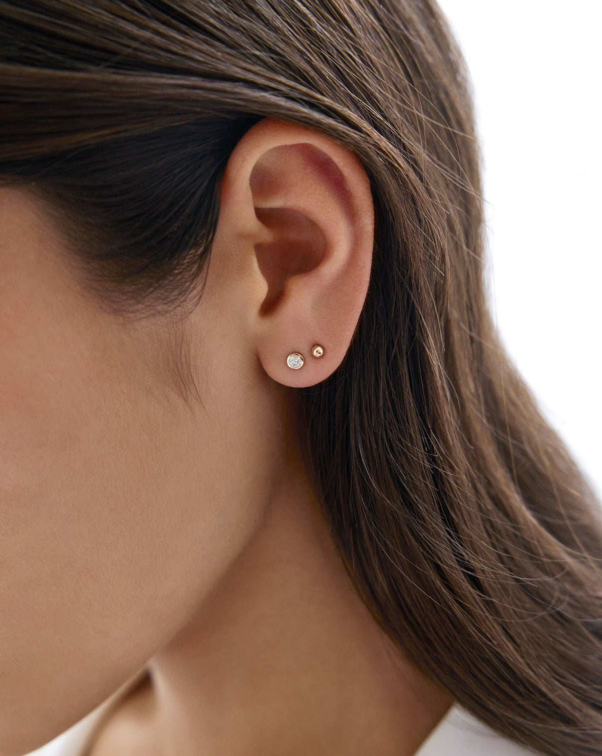 Petite Gold stud on model's earring styled with a bezel set diamond earring