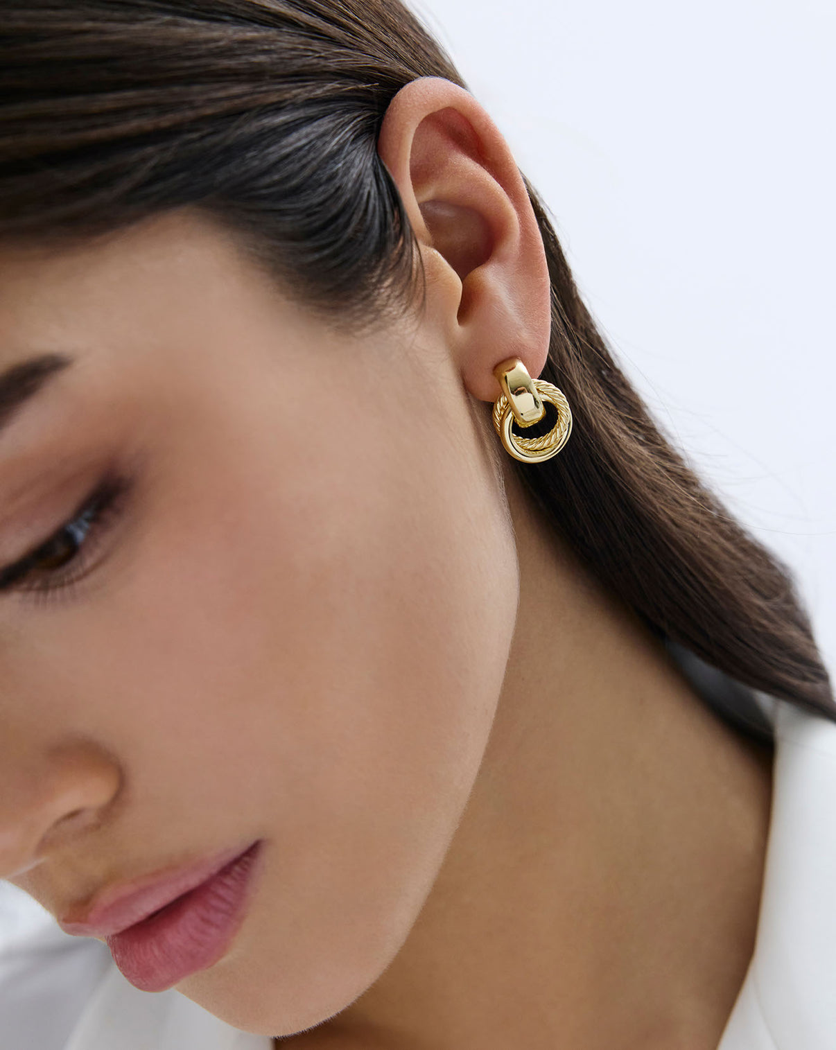 close up view of Textured door knocker earrings in yellow gold on-model