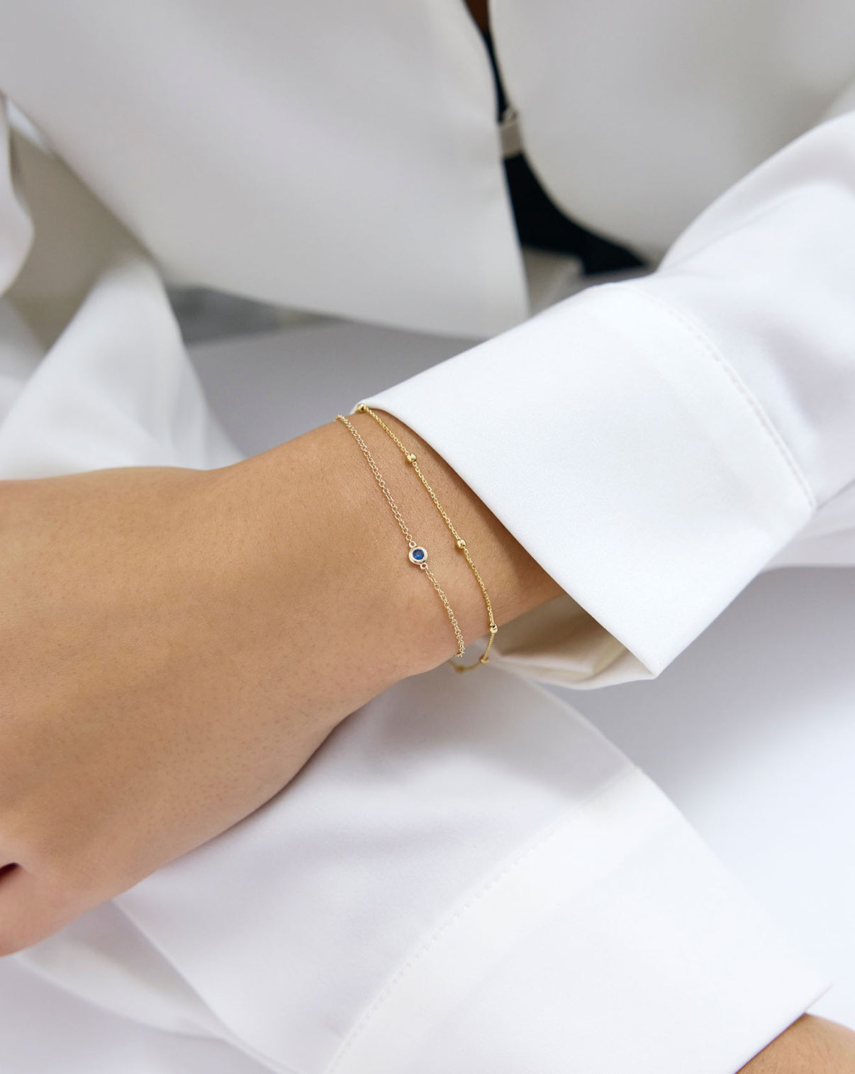 Saturn Chain Bracelet and Sapphire gem bracelet shown around wrist of model