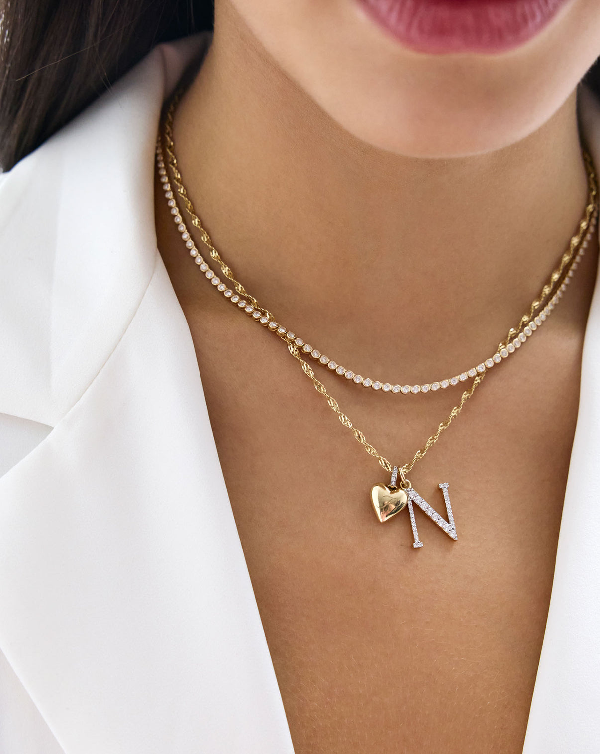 model wearing Twisted Yellow Gold Dorica Chain necklace styled with a heart and letter pendant, stacked with a diamond necklace