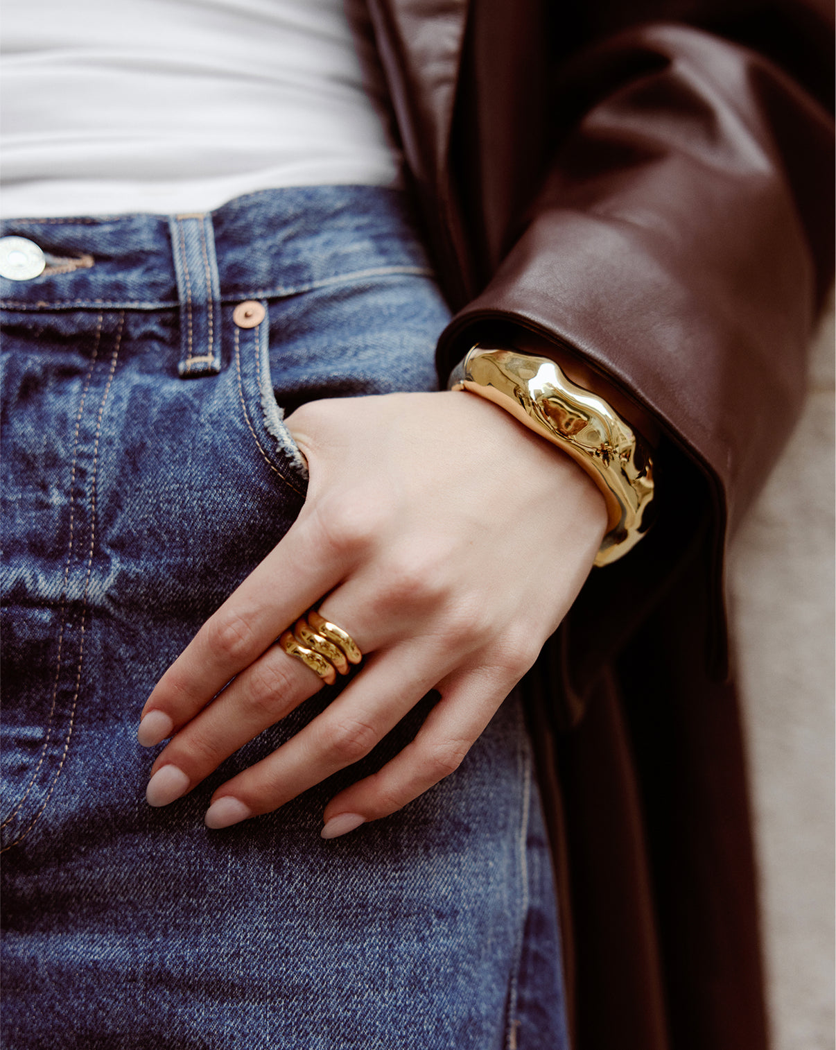 Close-up detail of Melted Bangle's unique sculptural texture and gold finish