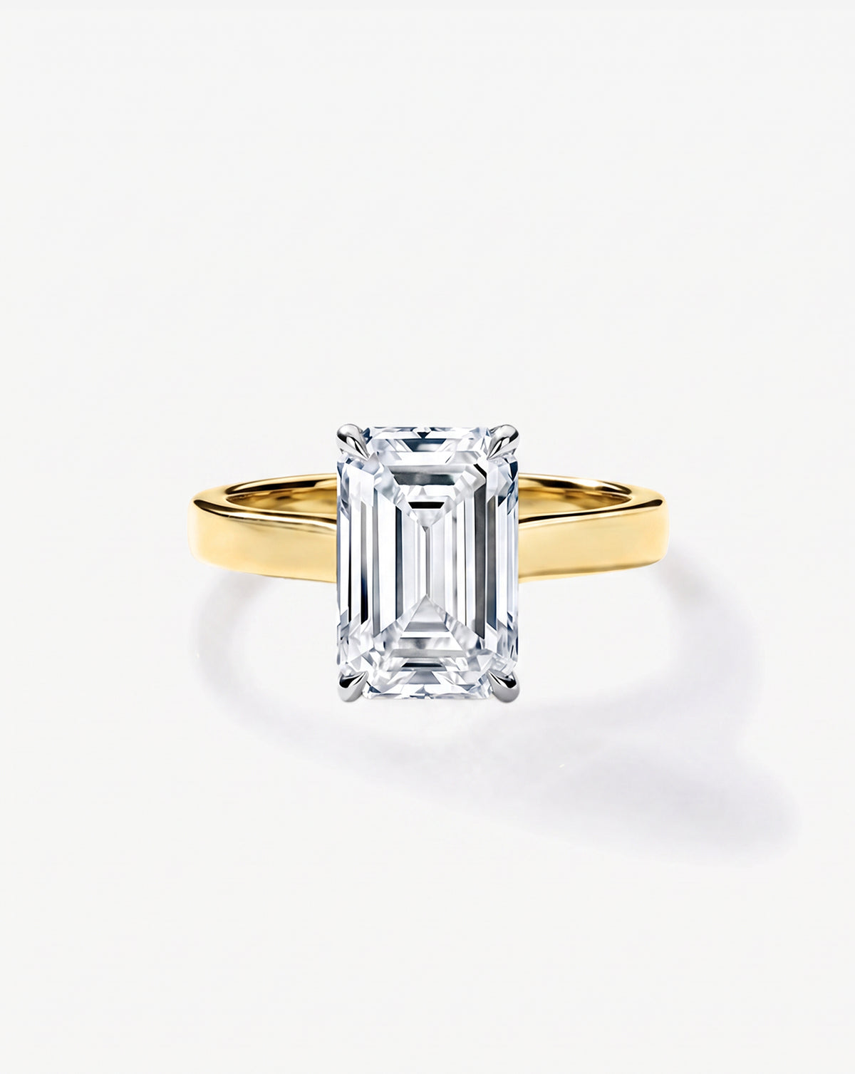 3.5 carat emerald cut lab-grown diamond engagement ring with cigar-style 14K yellow gold band and platinum prongs, front view on white background