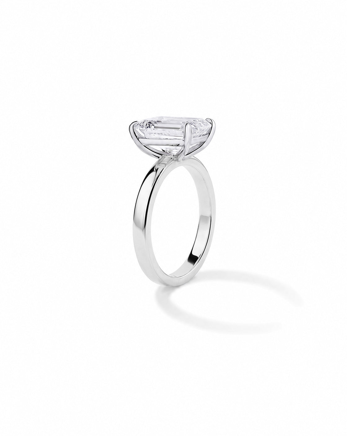Platinum engagement ring with an emerald diamond in a four-prong setting, on a cigar-style band, shown on a white background. 44830239326296