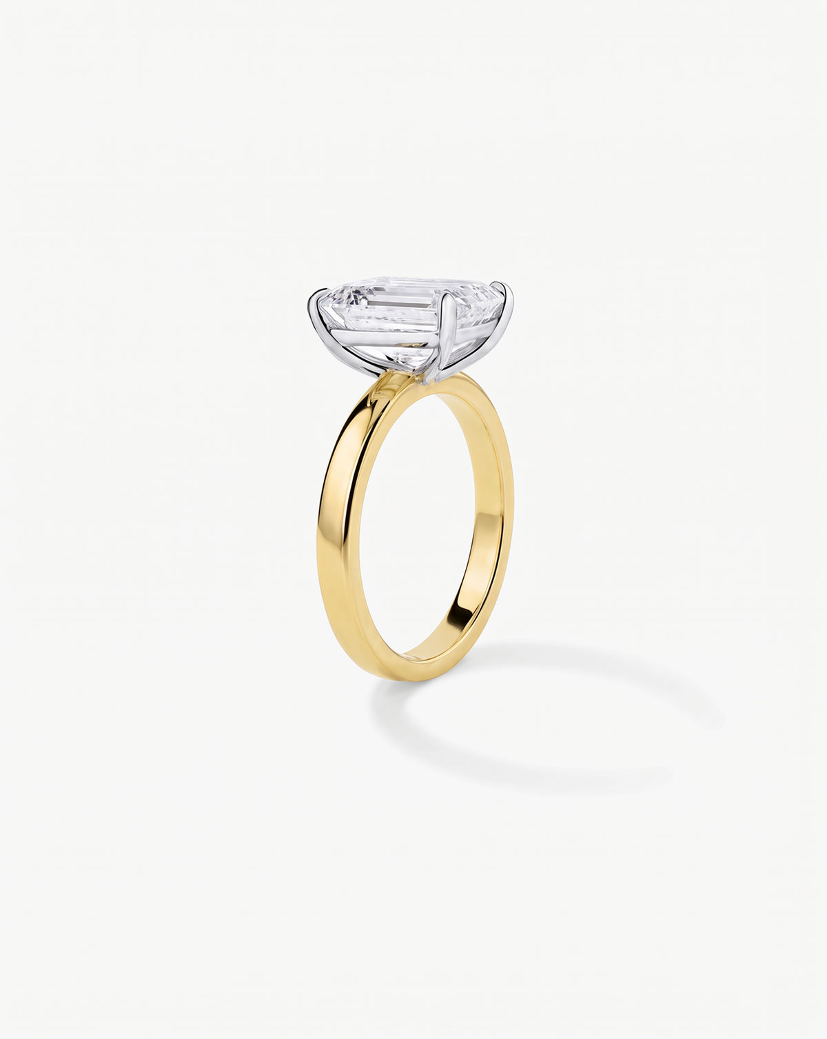 3.5 carat emerald cut lab-grown diamond engagement ring with cigar-style 14K yellow gold band and platinum prongs, front view on white background