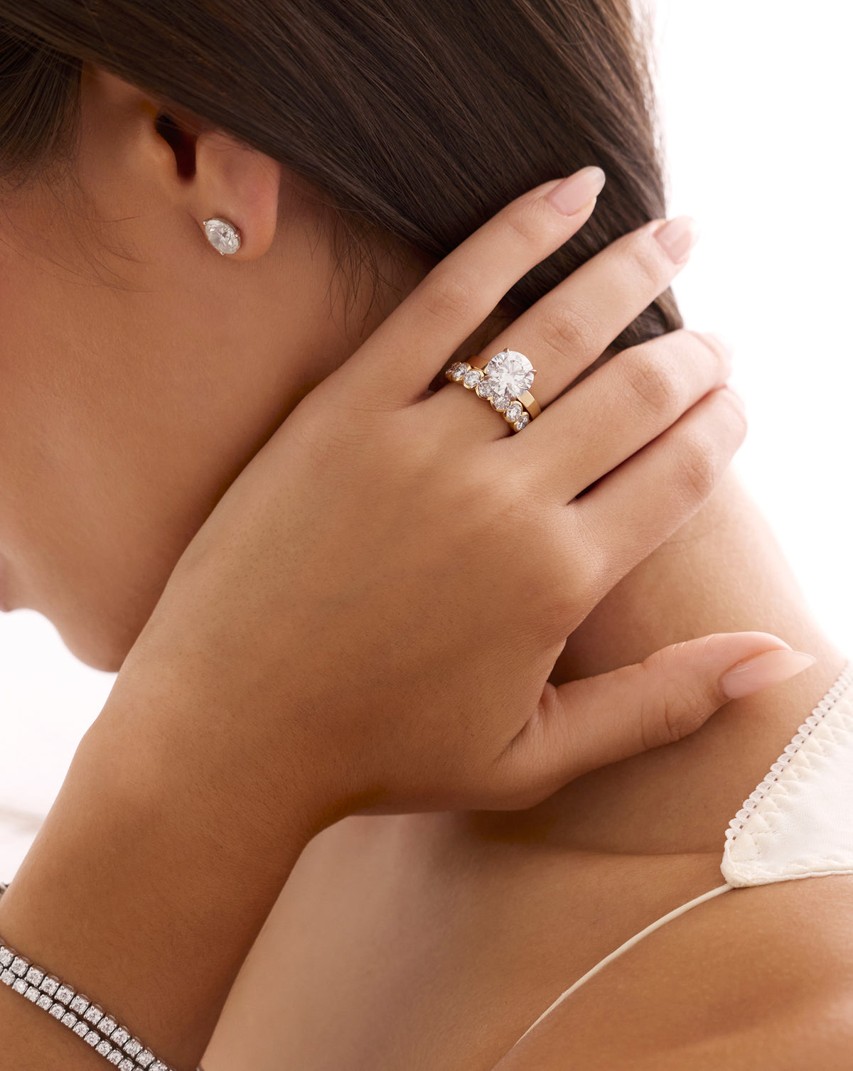 Woman holding her hair back, wearing a gold engagement ring with a round diamond and pavé band 44829996843096 44830238900312 44830239129688 