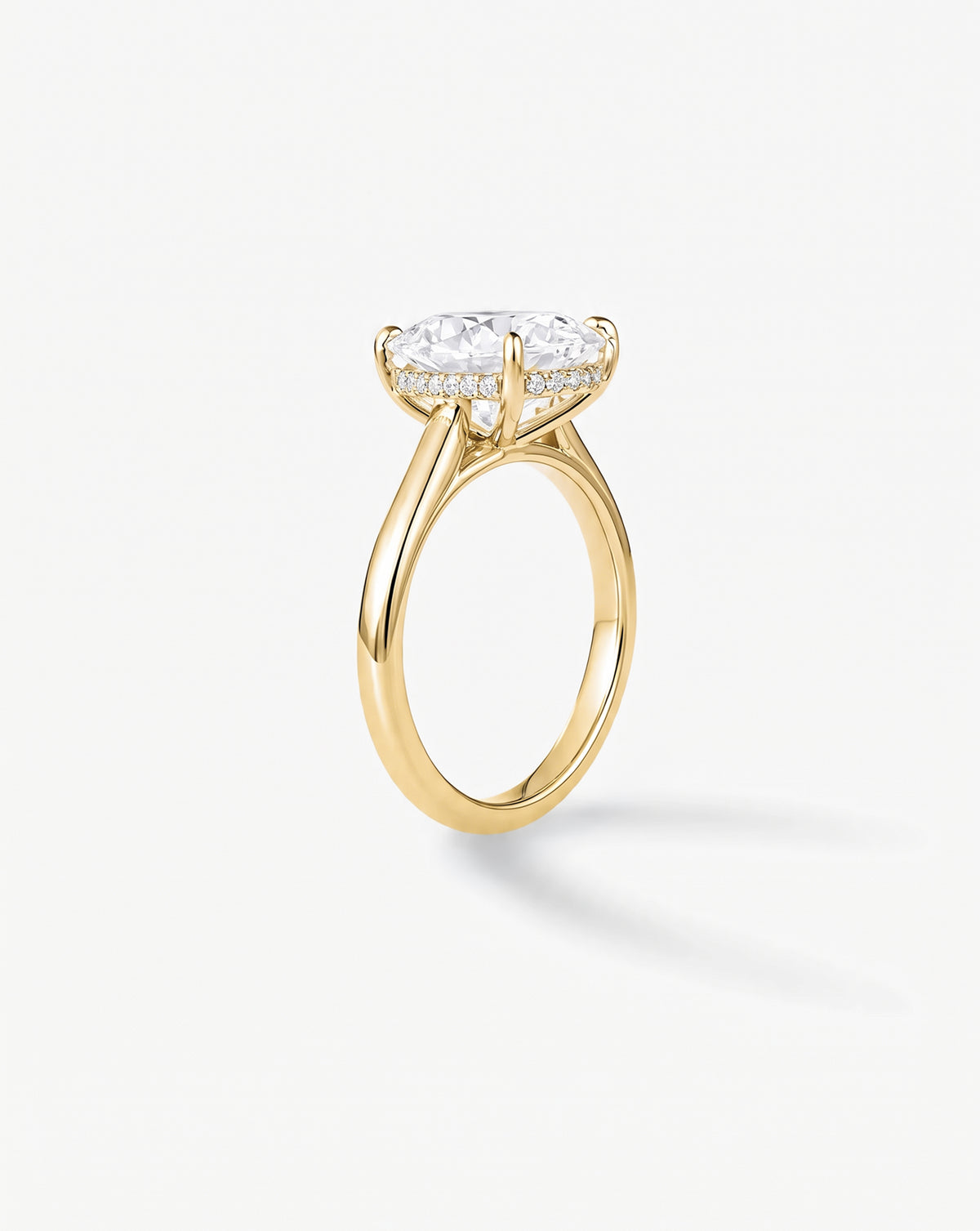 Side view of the 4.05 carat cushion cut lab-grown diamond engagement ring in a cathedral-style setting with 14K yellow gold band and platinum prongs, front view on white background