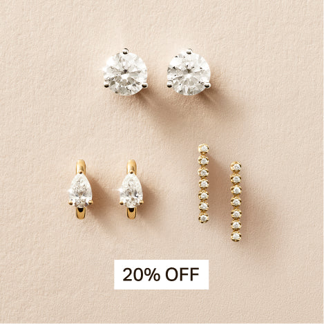 diamond stud earrings, pear diamond earrings, and tennis earrings against a travertine background