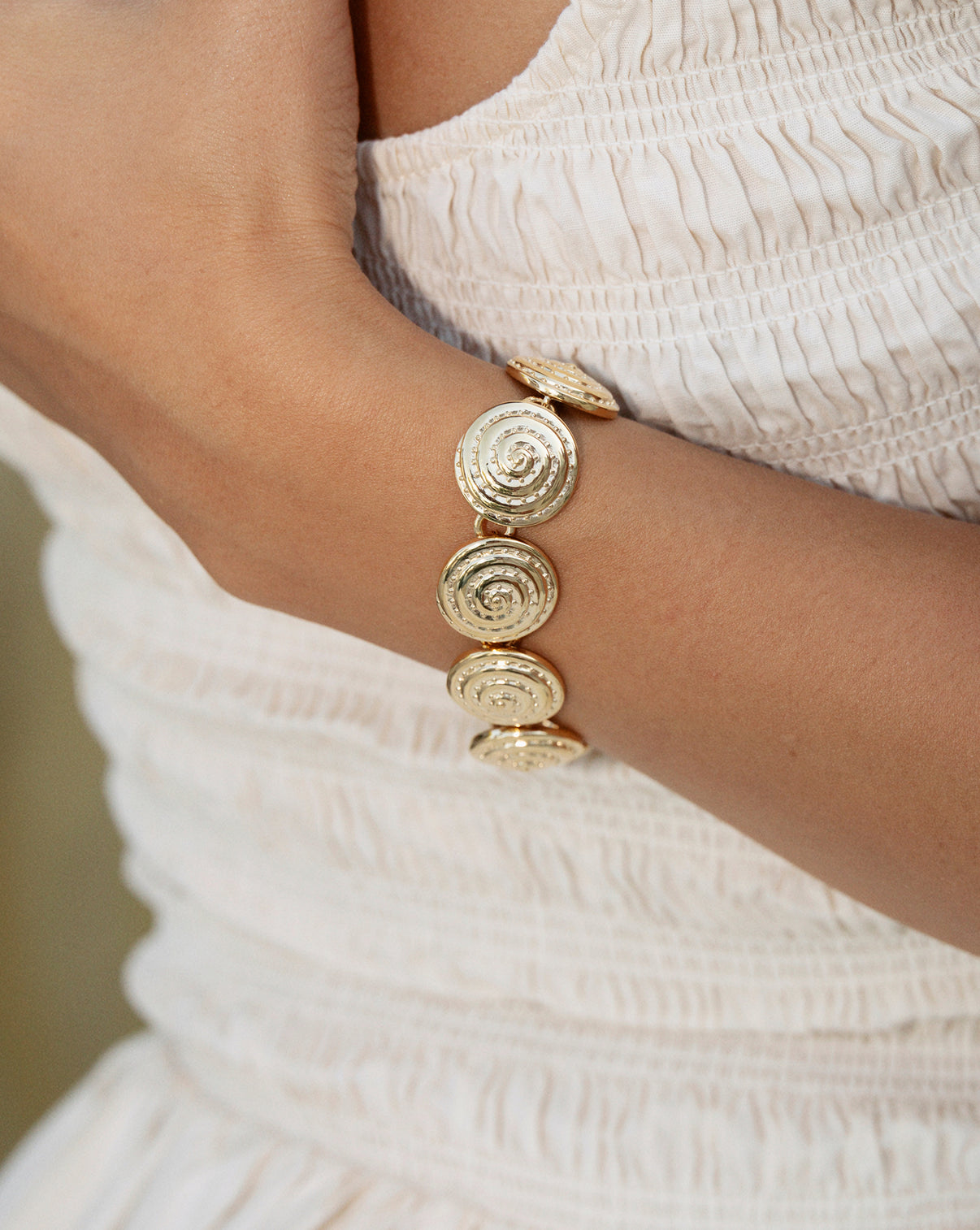Spiral bracelet on a wrist against a white dress
