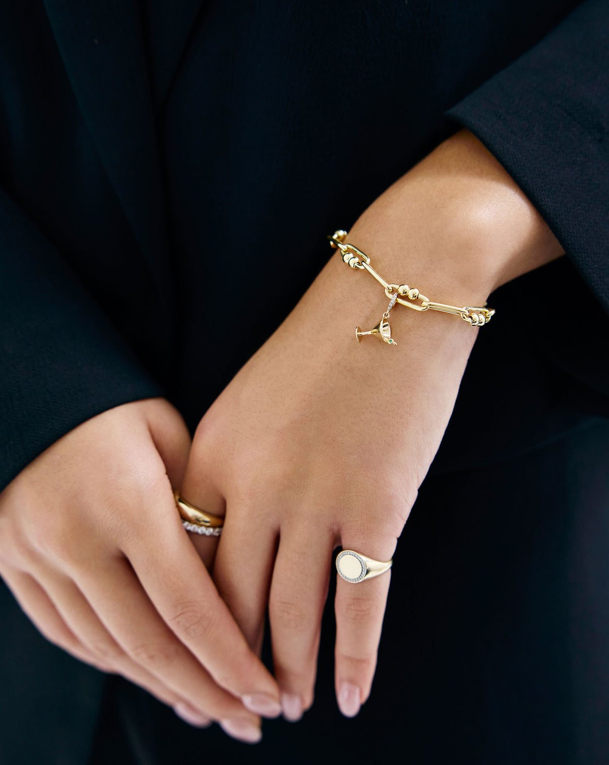 14k yellow gold dirty martini charm worn with gold bracelet on model's wrist